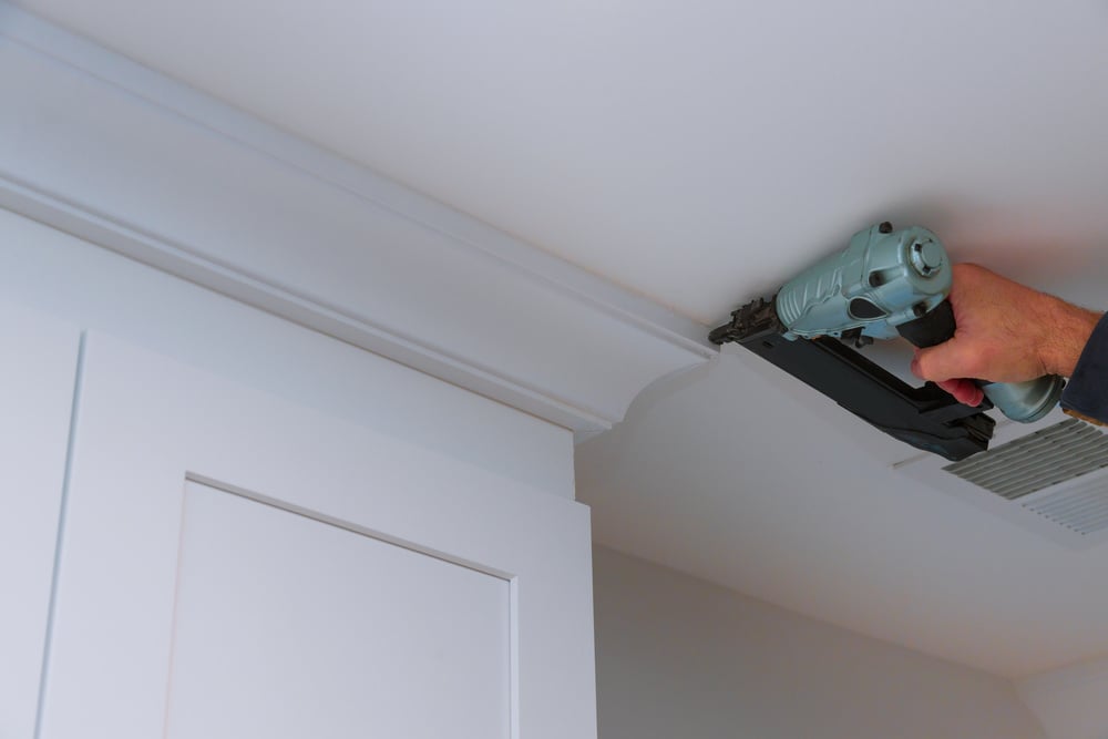 Carpenter Nailing Crown Moldings in the Kitchen Cabinets Framing Trim Worker Using Brad Nail Gun